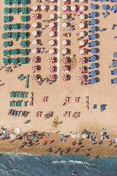 an aerial view of beach chairs and umbrellas on the sand next to the ocean