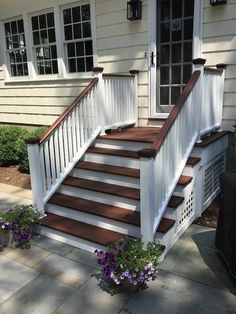 a white house with wooden steps and flowers