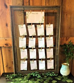 a wooden frame with notes attached to it and green leaves on the table next to it