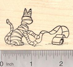 a rubber stamp with a drawing of a cat laying on the ground next to a roll of tape