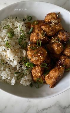 a white bowl filled with rice and meat on top of a marble countertop next to a fork