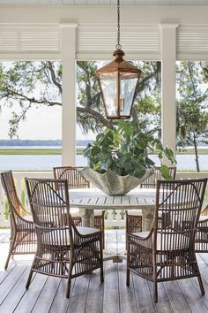 a dining room table with chairs and a lantern hanging from it's ceiling over a wooden deck