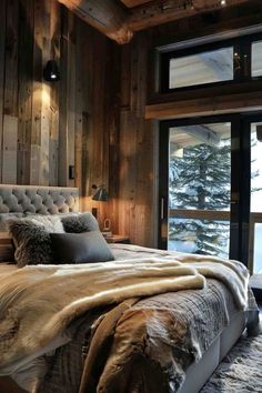 a bedroom with wood paneled walls and a large bed covered in furs, pillows and blankets