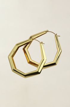 the large gold hoop earrings are hanging from a hook on a white background with no one in it