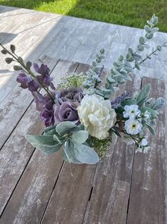 a vase filled with flowers sitting on top of a wooden table covered in greenery