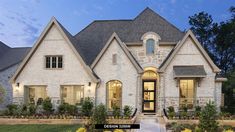 the front view of a home at dusk with landscaping around it and flowers on the lawn