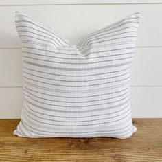 a white and grey striped pillow sitting on top of a wooden table