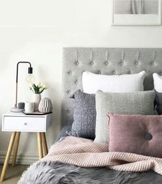 a bed with pillows and blankets on top of it in front of a white wall