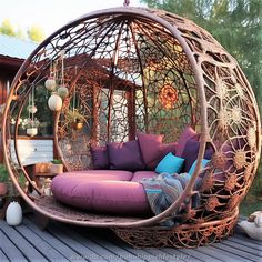 an outdoor swing chair with purple cushions and pillows on the outside deck, in front of a gazebo