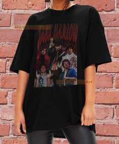 a woman standing in front of a brick wall wearing a black t - shirt with an image of the cast of harry potter on it