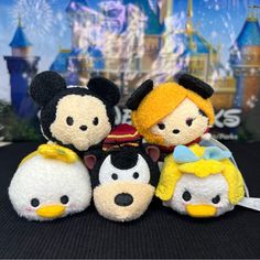 three small stuffed animals sitting next to each other in front of a disney world sign