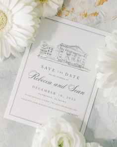 white flowers are on the table next to a wedding save the date card and envelope