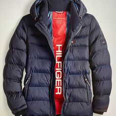 Stay Warm And Stylish With This Tommy Hilfiger Men's Puffer Jacket In Size Xl, Perfect For Any Occasion. Made With High Loft Insulation, This Jacket Provides Warmth Without Sacrificing Breathability. The Water And Wind-Resistant Nylon Outer Shell Material, Full Zip Closure, And Hooded Collar Make It Suitable For All Seasons. This Solid Blue Jacket Features A Tommy Hilfiger Logo And Accents, Zippered Pockets, And A Polyester Lining. It Is Machine Washable For Easy Care And Maintenance. Ideal For Functional Blue Outerwear With Double-lined Hood, Blue Nylon Outerwear With Double-lined Hood, Weatherproof Blue Outerwear For Streetwear, Blue Waterproof Hooded Winter Jacket, Functional Navy Outerwear For Cold Weather, Blue Down Outerwear With Double-lined Hood, Sporty Blue Weatherproof Outerwear, Sporty Blue Outerwear With Detachable Hood, Blue Weatherproof Puffer Jacket For Winter