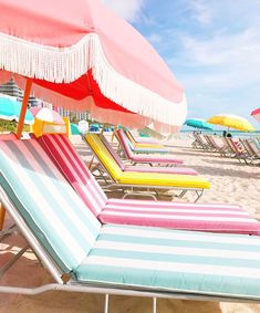 lounge chairs and umbrellas on the beach with blue skies in the backgroud