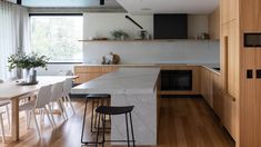 a kitchen with wooden cabinets and white counter tops, along with bar stools that match the hardwood flooring