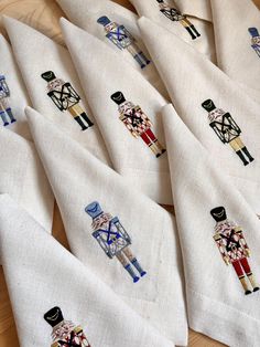 six embroidered napkins with different designs on them sitting on top of a wooden table