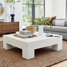 a living room with a couch, coffee table and vases on the floor in front of large windows