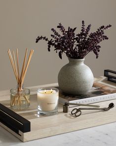 a table with a vase, candle and scissors on it next to a book that is open