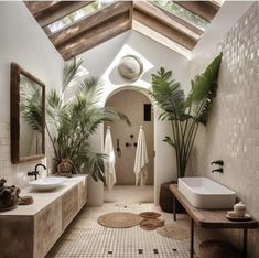 a large bathroom with two sinks and plants in the shower area, along with a skylight