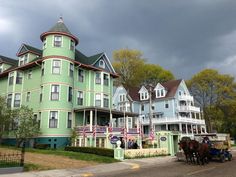 a horse drawn carriage is parked in front of a large green building with many windows