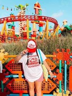 a woman standing in front of an amusement park roller coaster with her hands on her hips