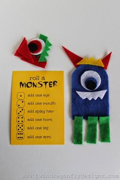 two felt monster puppets with instructions for each one on the front, and an orange paper sign that says roll a monster