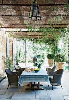 an outdoor dining area with wicker chairs and table surrounded by greenery on the patio