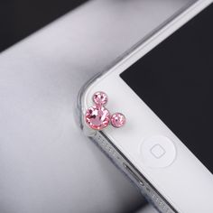 a cell phone with a pink bow brooch on it's back end and an iphone in the background