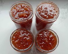 three jars filled with jam sitting on top of a counter