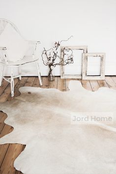 a white chair sitting on top of a wooden floor next to a vase filled with flowers