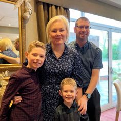 a man, woman and two children posing for a photo in front of a mirror