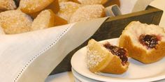 two white plates topped with pastries next to a basket of muffins on a table