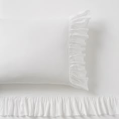 a white pillow with ruffled edges on a bed