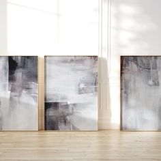 three abstract paintings are displayed in an empty room