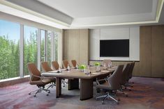 an empty conference room with chairs and a large table in front of a window overlooking the trees