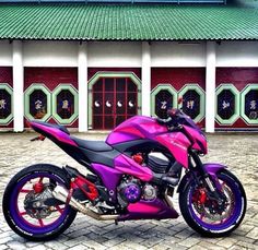 a purple and black motorcycle parked in front of a building