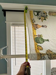 a person measuring the length of a window curtain with a tape measure on top of it