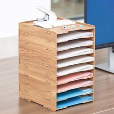 a stack of files sitting on top of a wooden desk next to a computer monitor