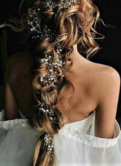 the back of a woman's head with long hair and flowers in her hair