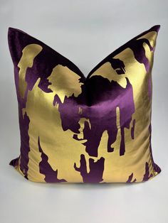 a purple and gold pillow sitting on top of a white table