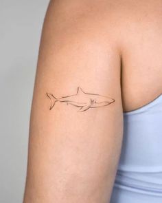 a woman's arm with a small tattoo of a shark on the left side