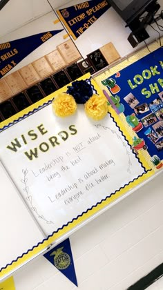 a sign that says wise words on it in front of a bulletin board with yellow flowers