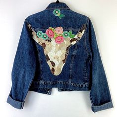 a denim jacket with flowers on the back and a giraffe's head painted on it