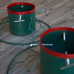 two green and red buckets sitting on top of a wooden floor next to each other