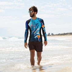 "There's nothing worse than sunburn, or bruises ruining a day filled with sports. But that's where this smooth and long-sleeved rash guard comes in play! It's slim-fitted, a bit longer than a casual tee, and tailor-made to protect from the sun, wind, and other elements while doing sports. Not to mention that it yields vibrant prints that'll get noticed. It has a four way stretch to allow the garment to hug and move with the body. It is moisture wicking, breathable and quick drying. Our rashguard Upf 50+ Crew Neck Swimwear, Crew Neck Swimwear With Upf 50+, Blue Crew Neck Tops For Water Sports, Casual Rash Guard For Surfing With Upf 50+, Summer Crew Neck Rash Guard For Surfing, Casual Blue Crew Neck Swimwear, Casual Crew Neck Swimwear For Swimming, Sporty Crew Neck Swimwear For Beach, Crew Neck Swimwear For Surfing In Summer