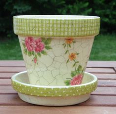 a green and white flower pot sitting on top of a wooden table next to a bowl