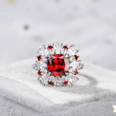 Displaying vivacious feminine flair, this striking fashion ring highlights all that makes her truly exceptional. Crafted in sterling silver, this pretty and unconventional look showcases an cushion cut center stone. Oval cut stones, white round stones and red round stones wrap the centerpiece in a sparkling embrace. Buffed to a brilliant luster, this fabulous conversation piece is sure to be admired often.Carat Weight: 3.7 ctStone Size: 8*8 mmStone Type: Jeulia® StoneNumber of Stones: 1 Stone Color: Garnet RedStone Shape: CushionCarat Weight: 0.62 ctStone Size: 2.3,2 mmStone Type: Jeulia® StoneNumber of Stones: 9 Stone Color: Garnet Red, Diamond WhiteStone Shape: RoundWeight: 6.48 gWidth: 16.4 mmHeight: 8.3 mmThickness: 2.8 mmMaterial: 925 SilverPlating Color: Silver Red Diamond Ring With Brilliant Cushion Cut, Red Cushion Cut Brilliant Diamond Ring, Red Cushion Cut Diamond Ring With Brilliant Cut, Ruby Ring With Radiant Cut Center Stone, Red Diamond Ring With Center Cushion Cut, Elegant Cushion Cut Ruby Ring For Wedding, Elegant Cushion Cut Ruby Wedding Ring, Red Cushion Cut Brilliant Ring, Elegant Cushion Cut Gemstone Halo Ring