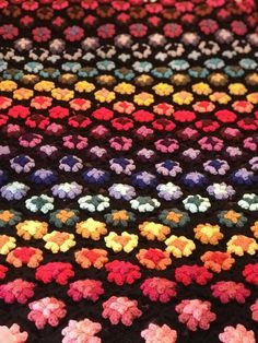 a multicolored crocheted blanket with flowers on it