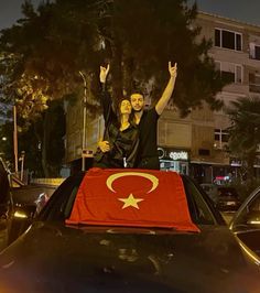 two people waving from the back of a car