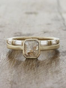 an engagement ring with two baguets and a stone in the center on a wooden surface